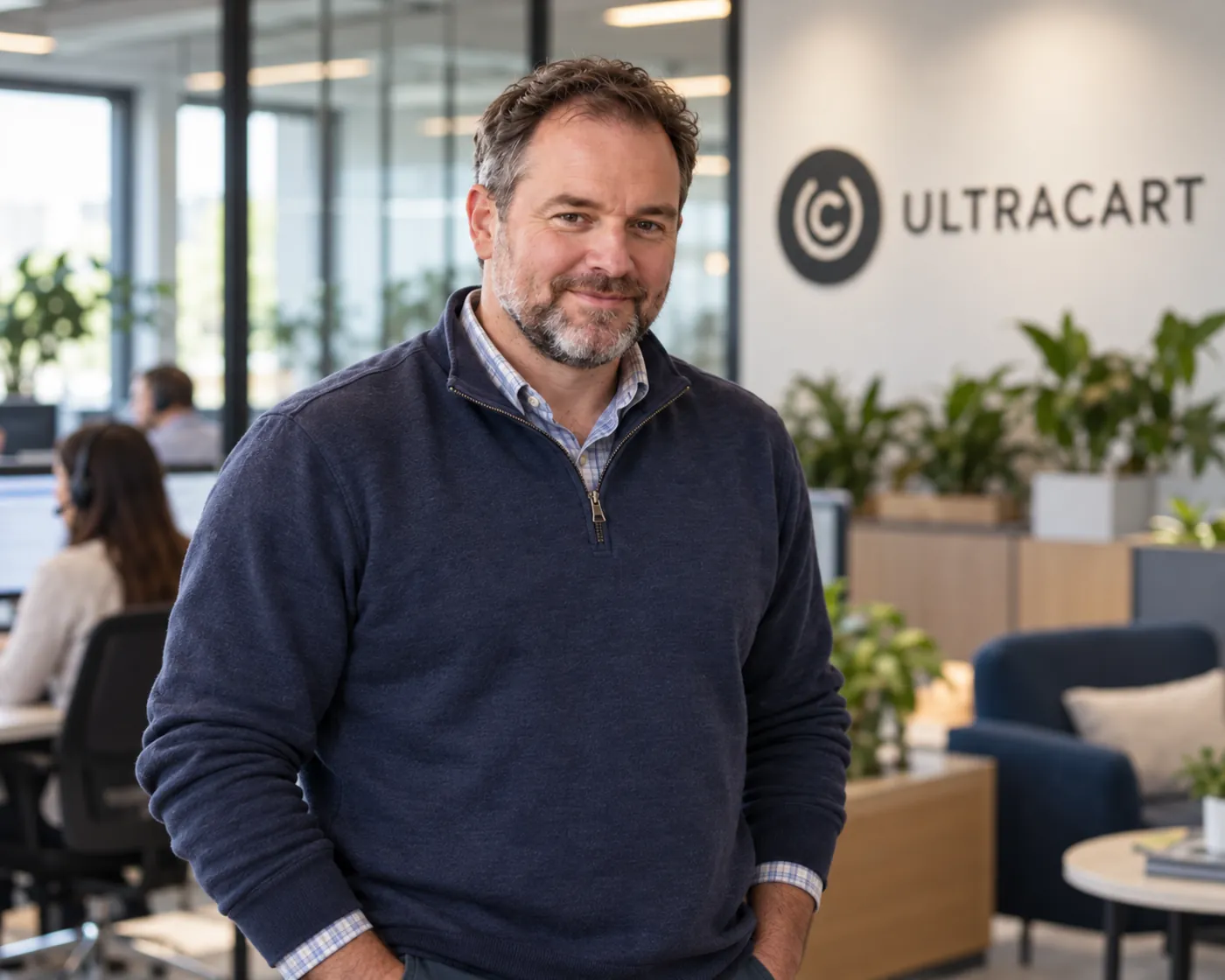 UltraCart team member in the UltraCart office with the support team working behind him
